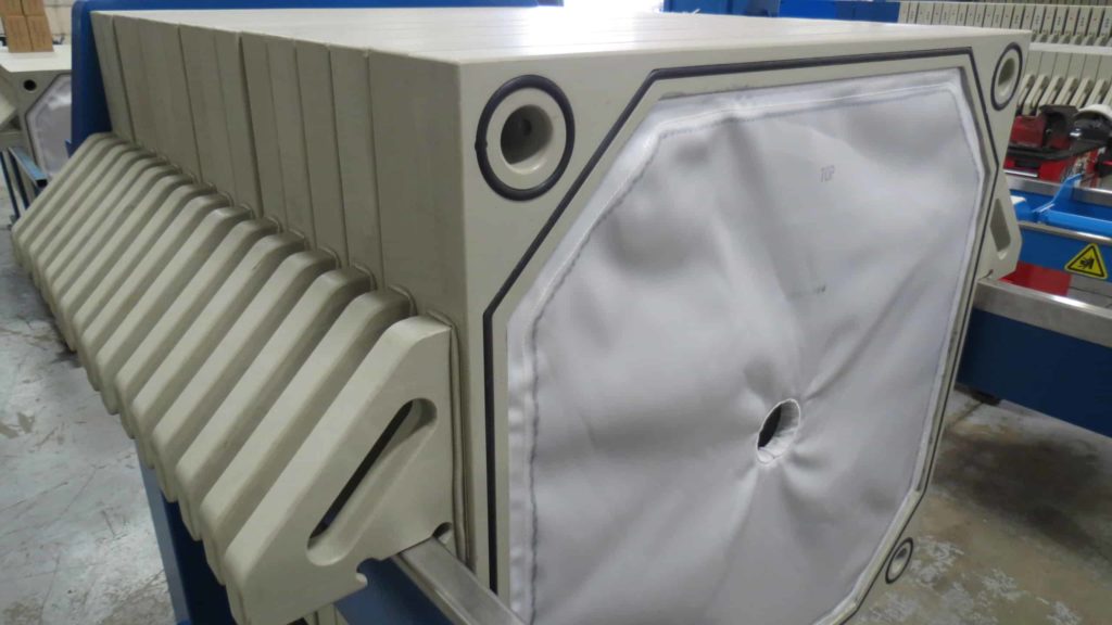 M.W. Watermark Gasketed Polypropylene Recessed Chamber Filter Plates in a Press with Cloths Installed. Solids Accumulate on the Surface of the Cloths to Form a Filter Cake.